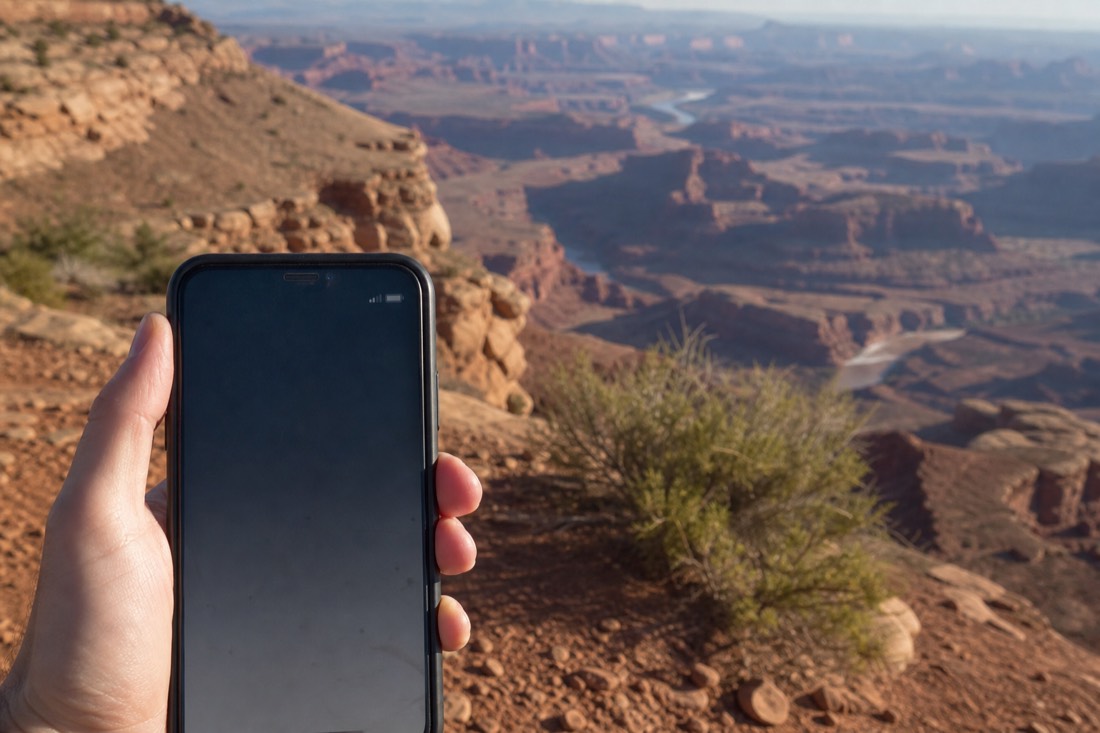 Phone showing a single signal bar at a remote rim drive pullout with empty canyon country beyond