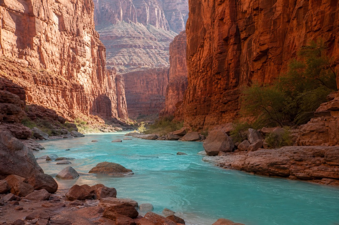 Turquoise water of a canyon creek framed by towering red walls on tribal land in the western Grand Canyon