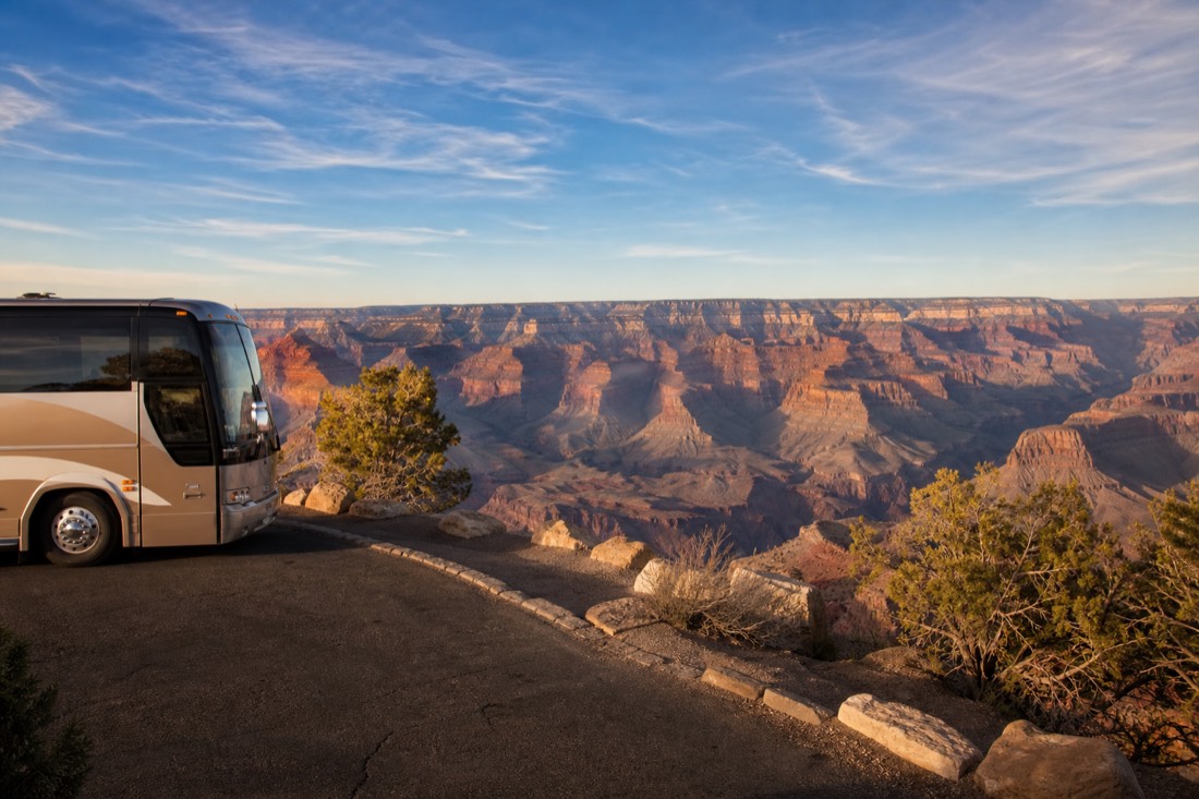 A comfortable touring coach parked at a South Rim overlook with visitors stepping off slowly