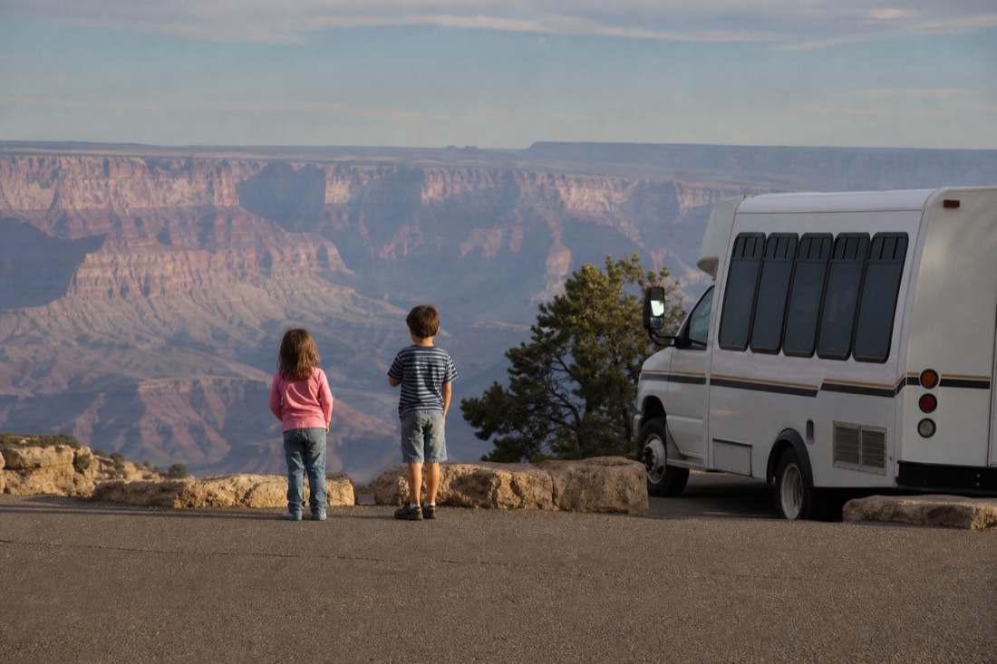 Children on a level viewing platform above the western canyon with a shuttle bus waiting behind them