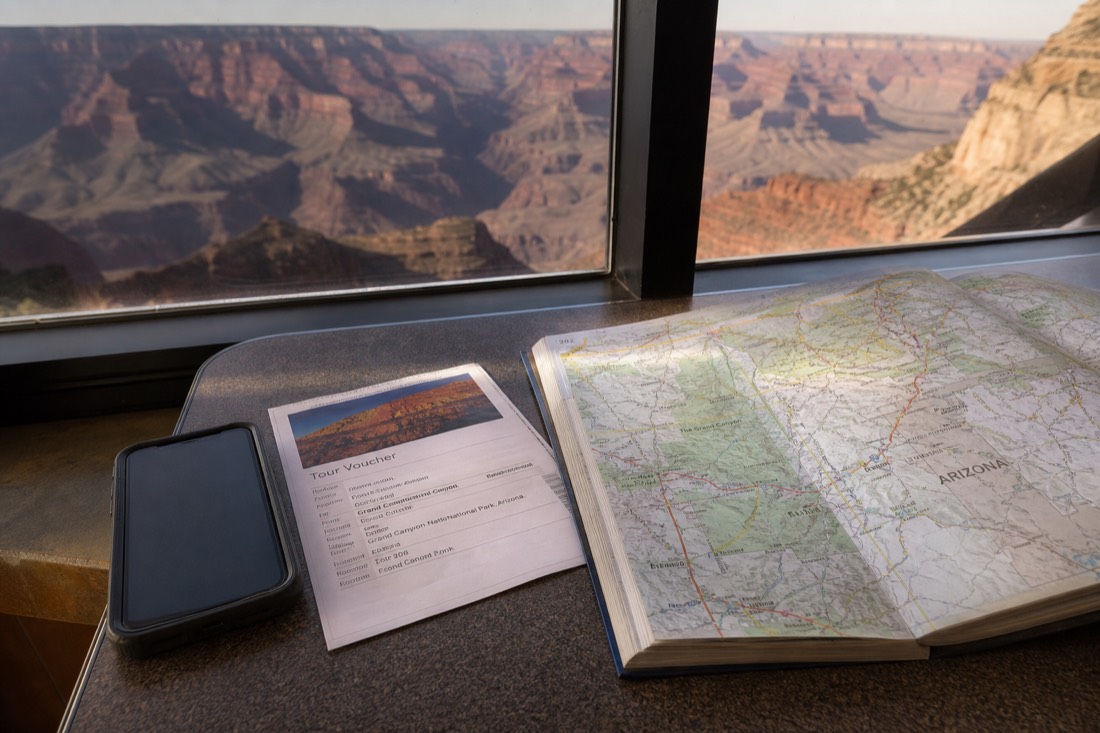 Phone and printed tour voucher on a diner table beside a road atlas open to northern Arizona