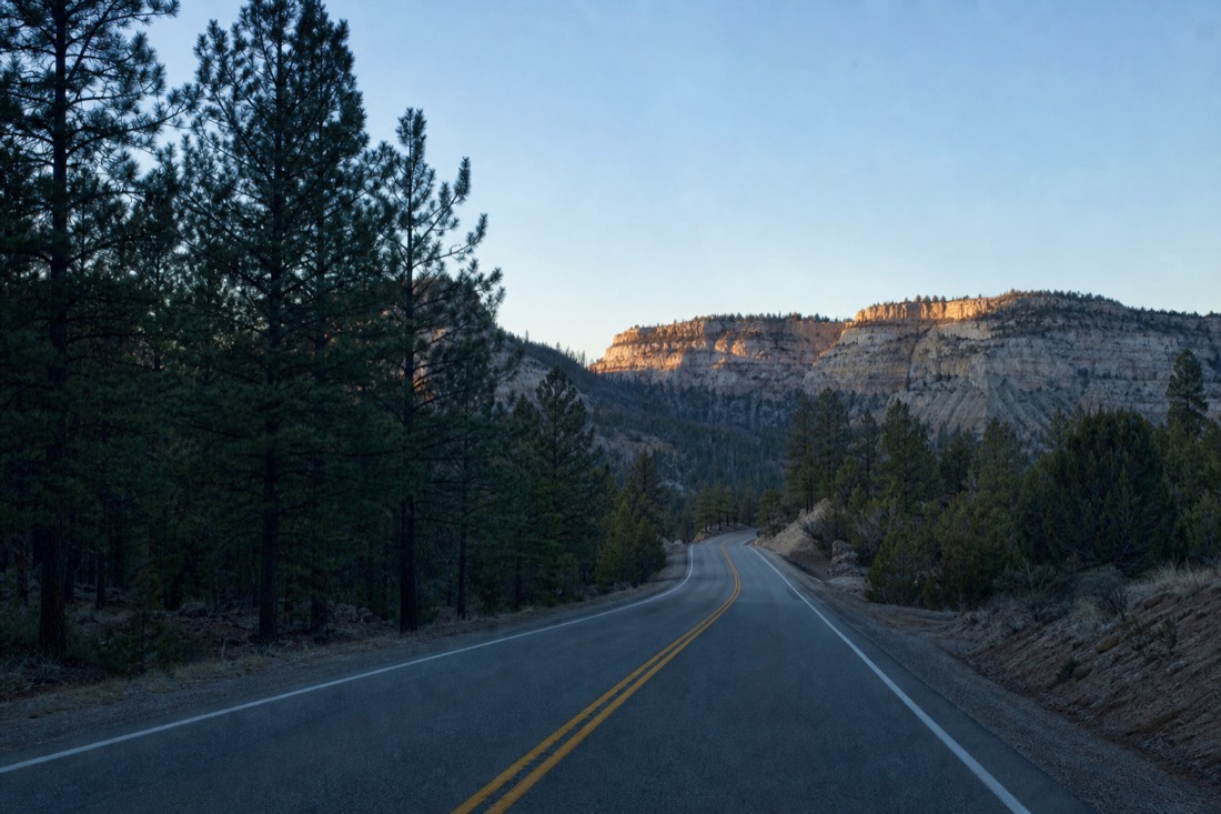 Empty two-lane highway 64 running north through ponderosa forest in pre-dawn blue light