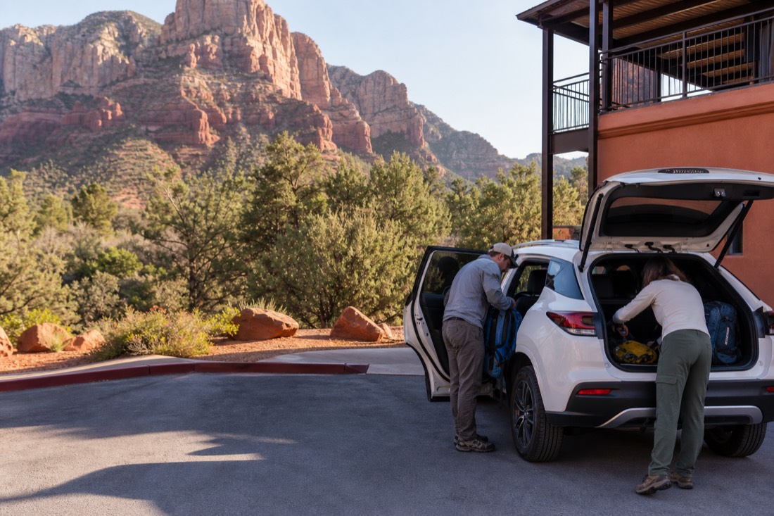 Family loading daypacks into a car outside a mountain-town hotel on a bright Arizona morning