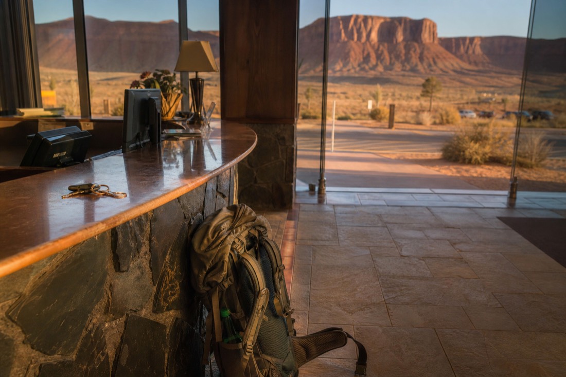 Traveller at a hotel front desk in the early morning with a daypack and car keys on the counter